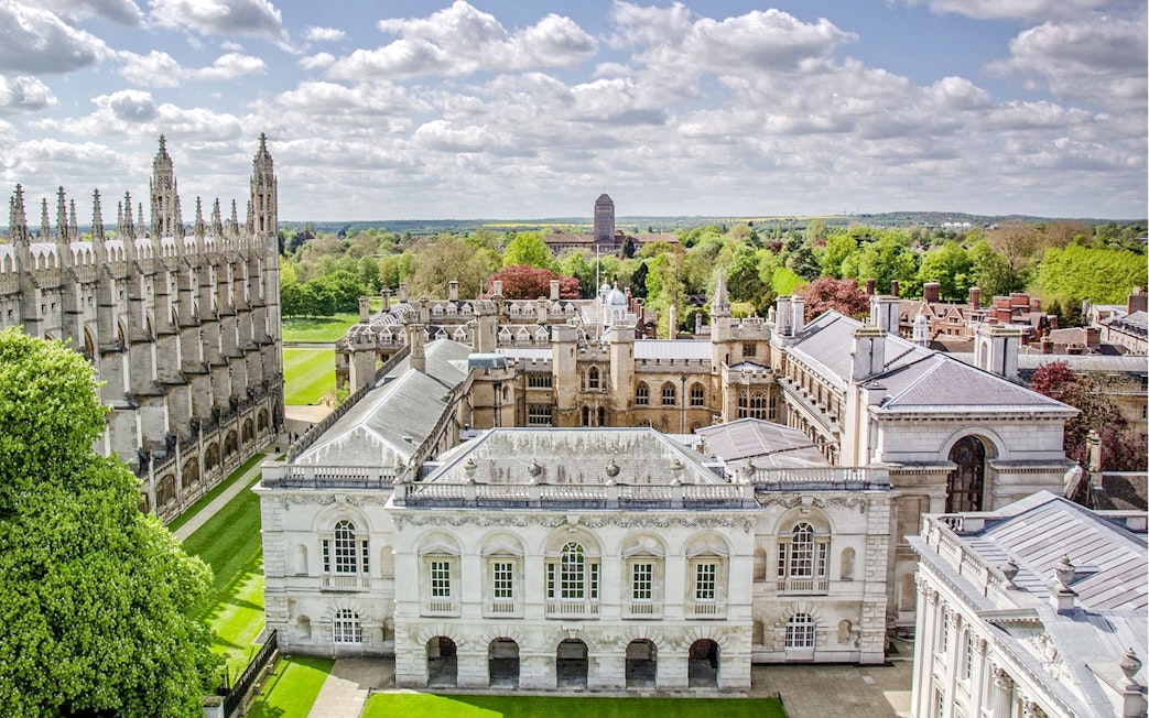 Aerial view of Cambridge University buildings and green lawns on a sunny day.