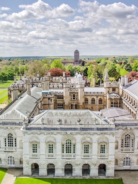 Aerial view of Cambridge University buildings and green lawns on a sunny day.