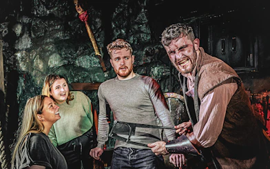 Guests interacting with actor in London Dungeon Torture Chamber.