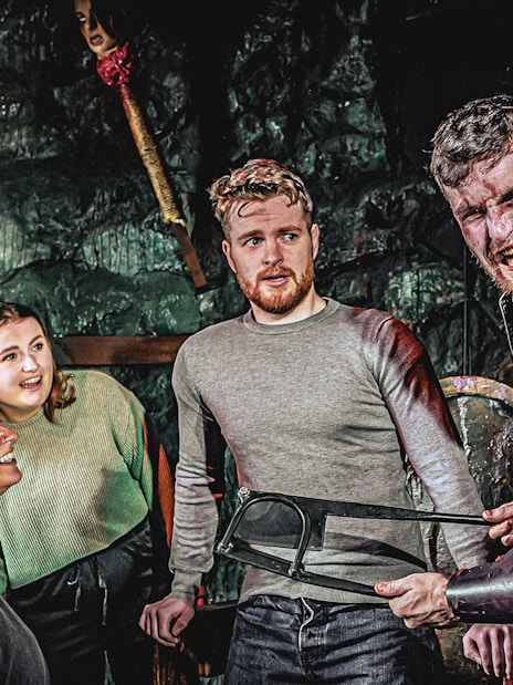 Guests interacting with actor in London Dungeon Torture Chamber.