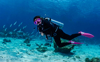 Scuba diver exploring coral reef with fish, Racha Island, Phuket.