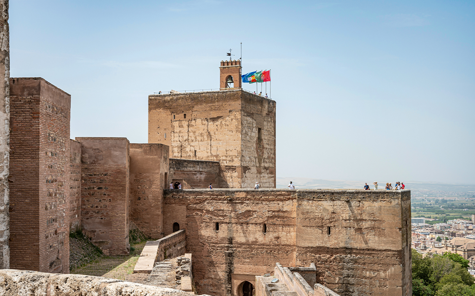 Alhambra fortress walls with tourists exploring the historic site in Granada, Spain.