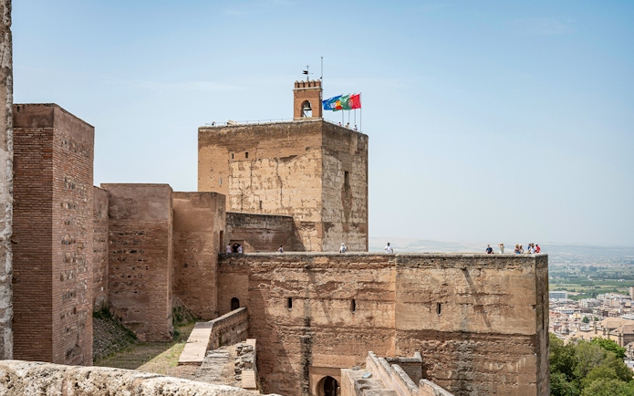 Alhambra fortress walls with tourists exploring the historic site in Granada, Spain.