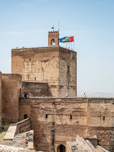 Alhambra fortress walls with tourists exploring the historic site in Granada, Spain.