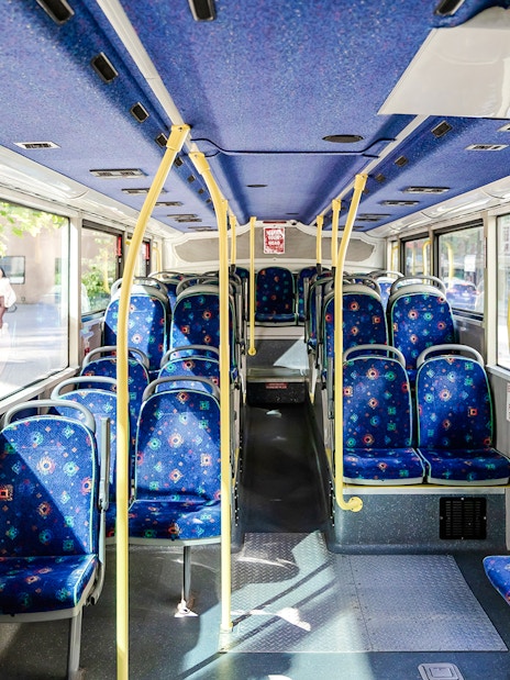 Interior of a Big Bus Vancouver tour bus with empty blue patterned seats.