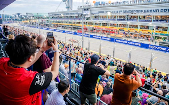 Crowd watching the Singapore Grand Prix race from the stands, capturing the vibrant atmosphere.