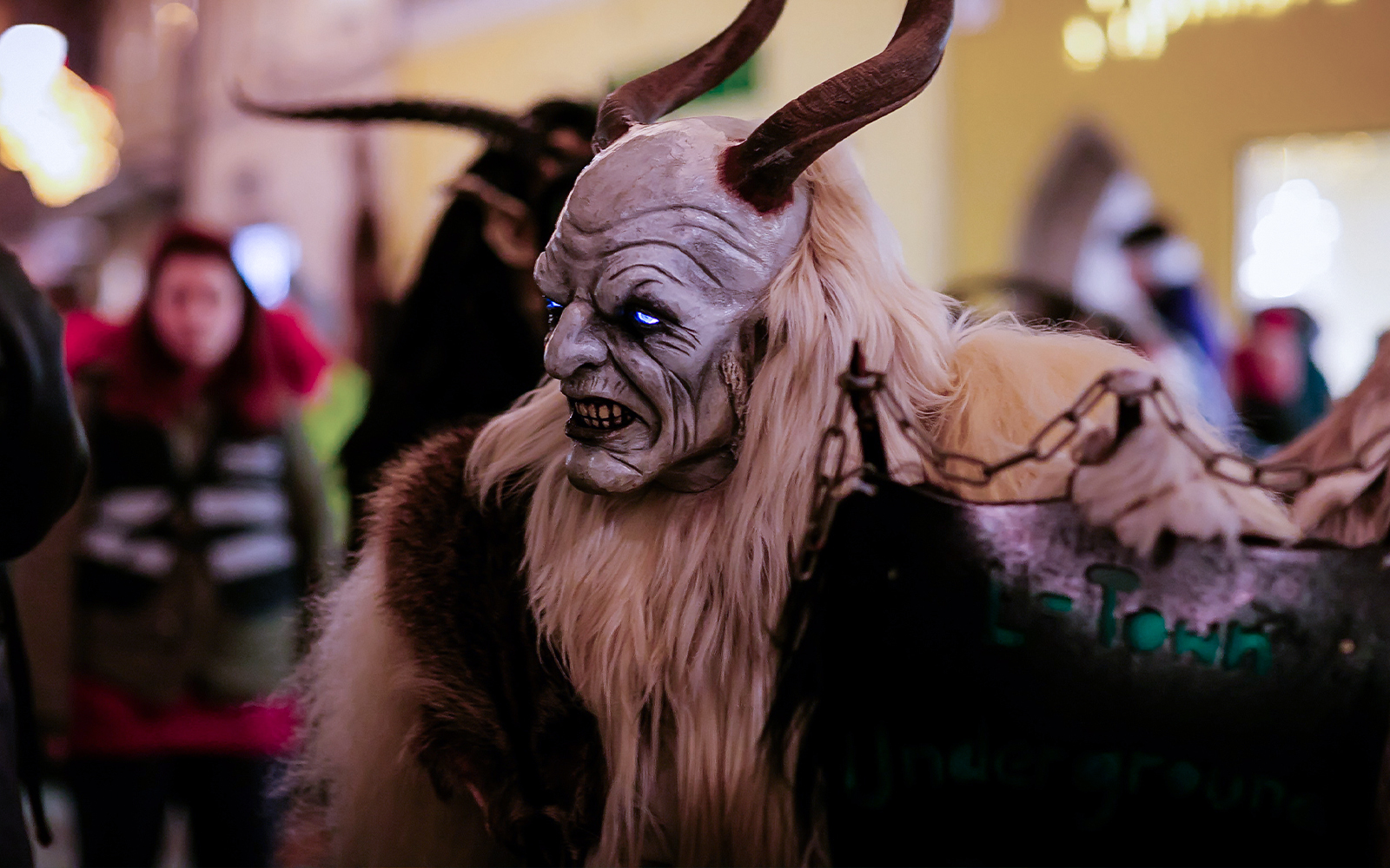 Costumed figure with horns and glowing eyes at a Halloween parade.