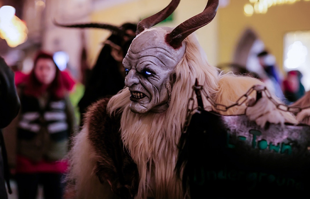 Costumed figure with horns and glowing eyes at a Halloween parade.