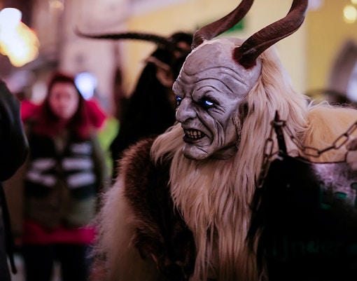 Costumed figure with horns and glowing eyes at a Halloween parade.