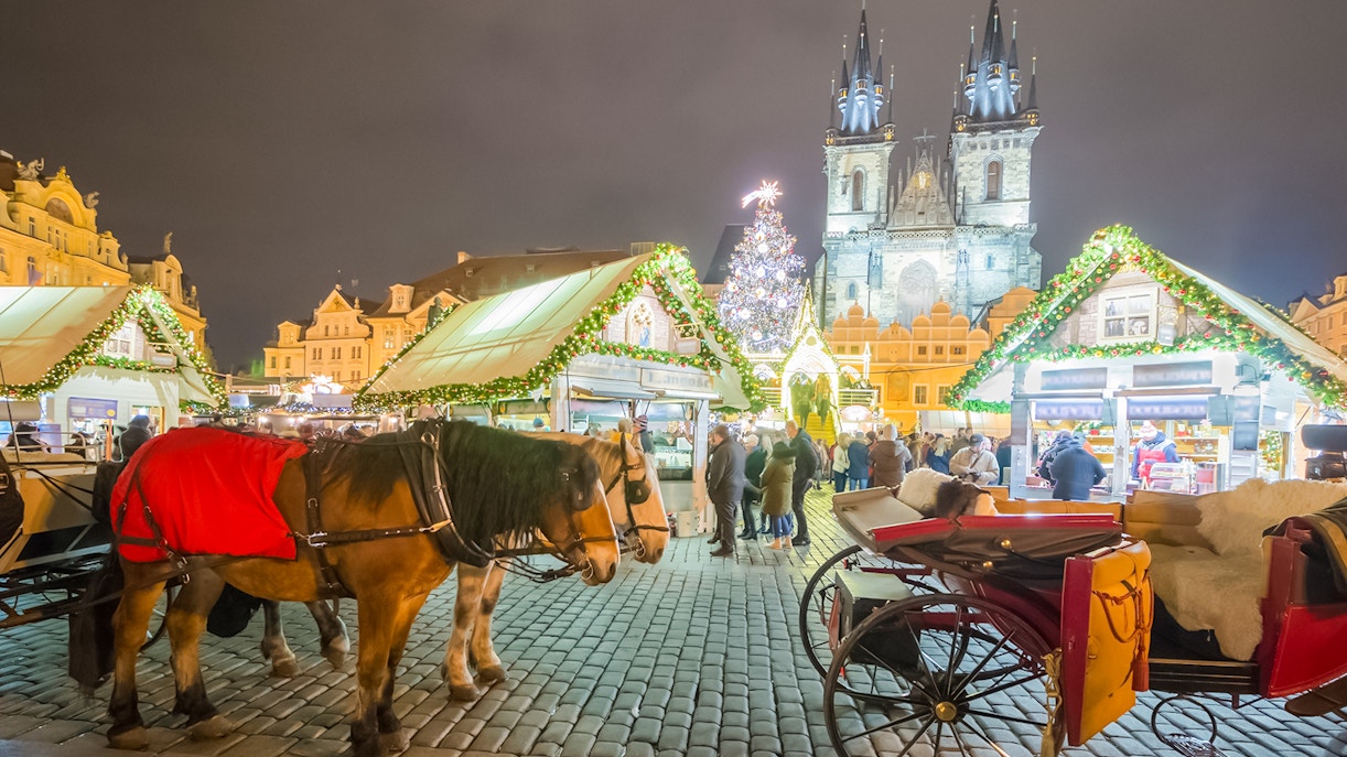 Horse-drawn carriage at Prague Castle Christmas market with festive lights and stalls.