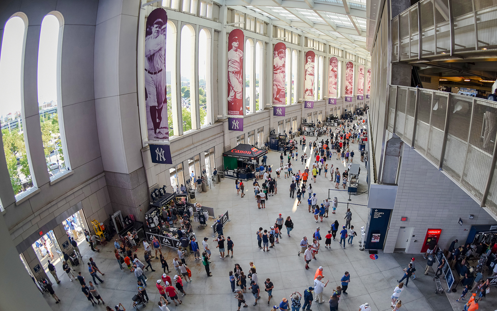 Yankee Stadium concourse with fans and historic player banners.