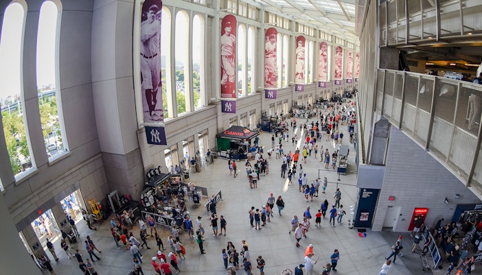 Yankee Stadium concourse with fans and historic player banners.