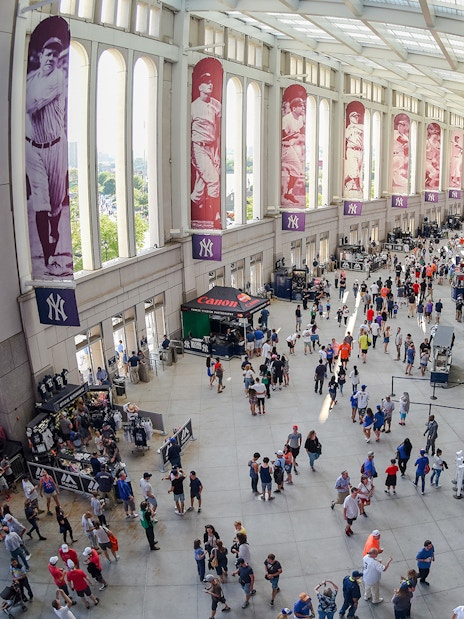 Yankee Stadium concourse with fans and historic player banners.