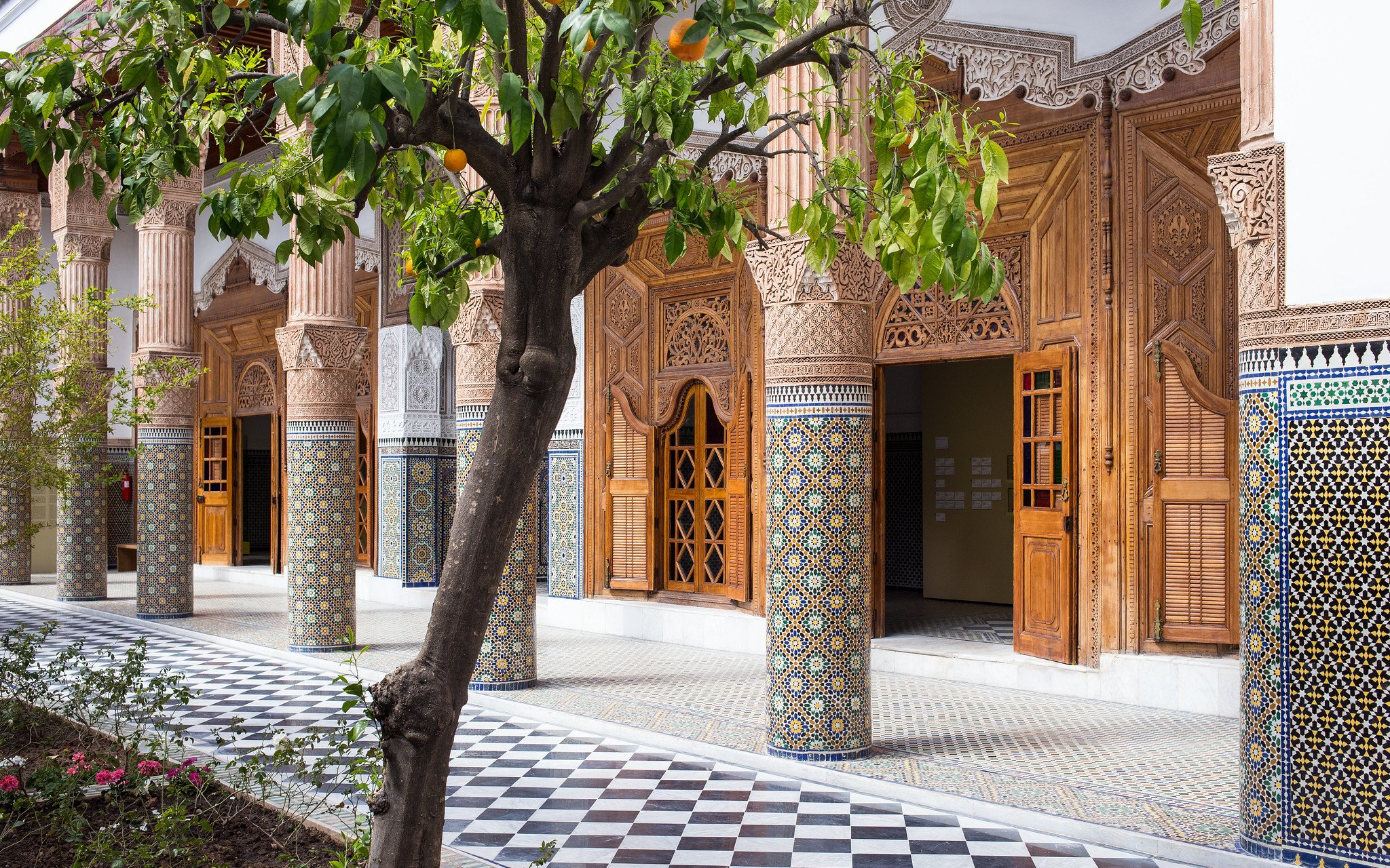 Ben Youssef Medersa courtyard with intricate tilework and carved wooden doors, Marrakech.