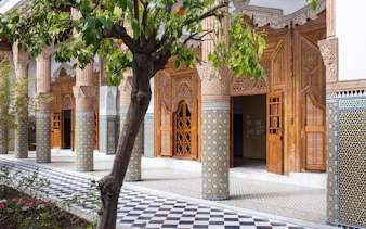 Ben Youssef Medersa courtyard with intricate tilework and carved wooden doors, Marrakech.