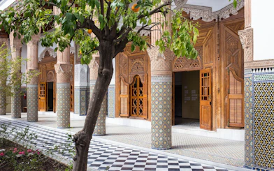 Ben Youssef Medersa courtyard with intricate tilework and carved wooden doors, Marrakech.