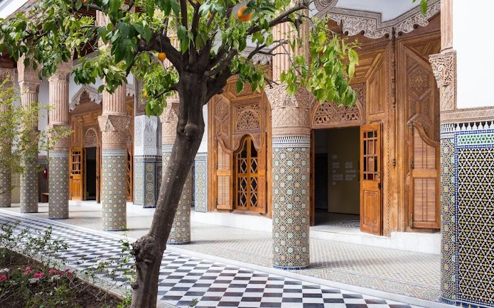Ben Youssef Medersa courtyard with intricate tilework and carved wooden doors, Marrakech.