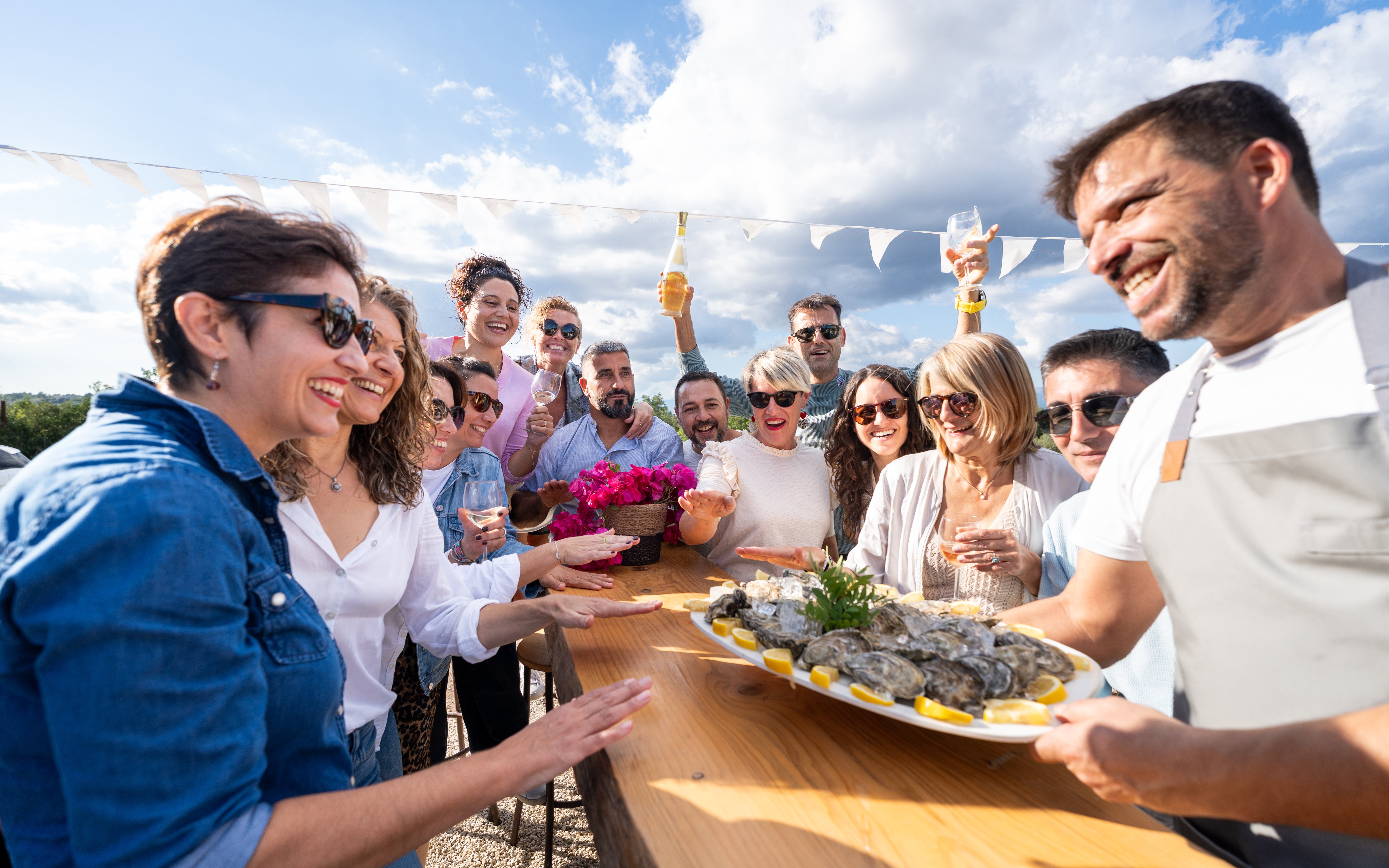 Friends enjoying oysters at an outdoor bar, sharing food and drinks.