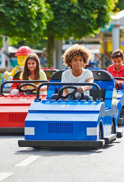 Children driving mini cars at Legoland Windsor Resort, London.