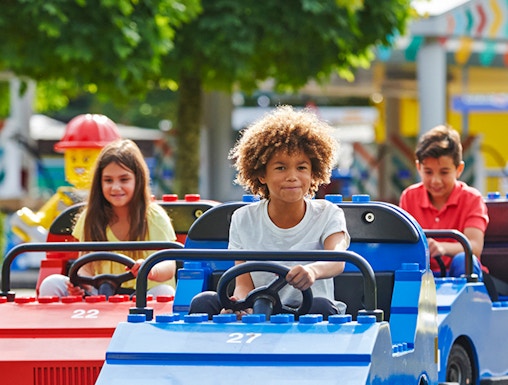Children driving mini cars at Legoland Windsor Resort, London.