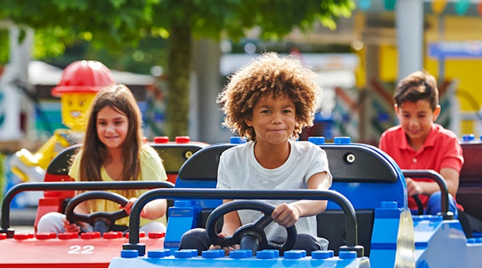 Children driving mini cars at Legoland Windsor Resort, London.