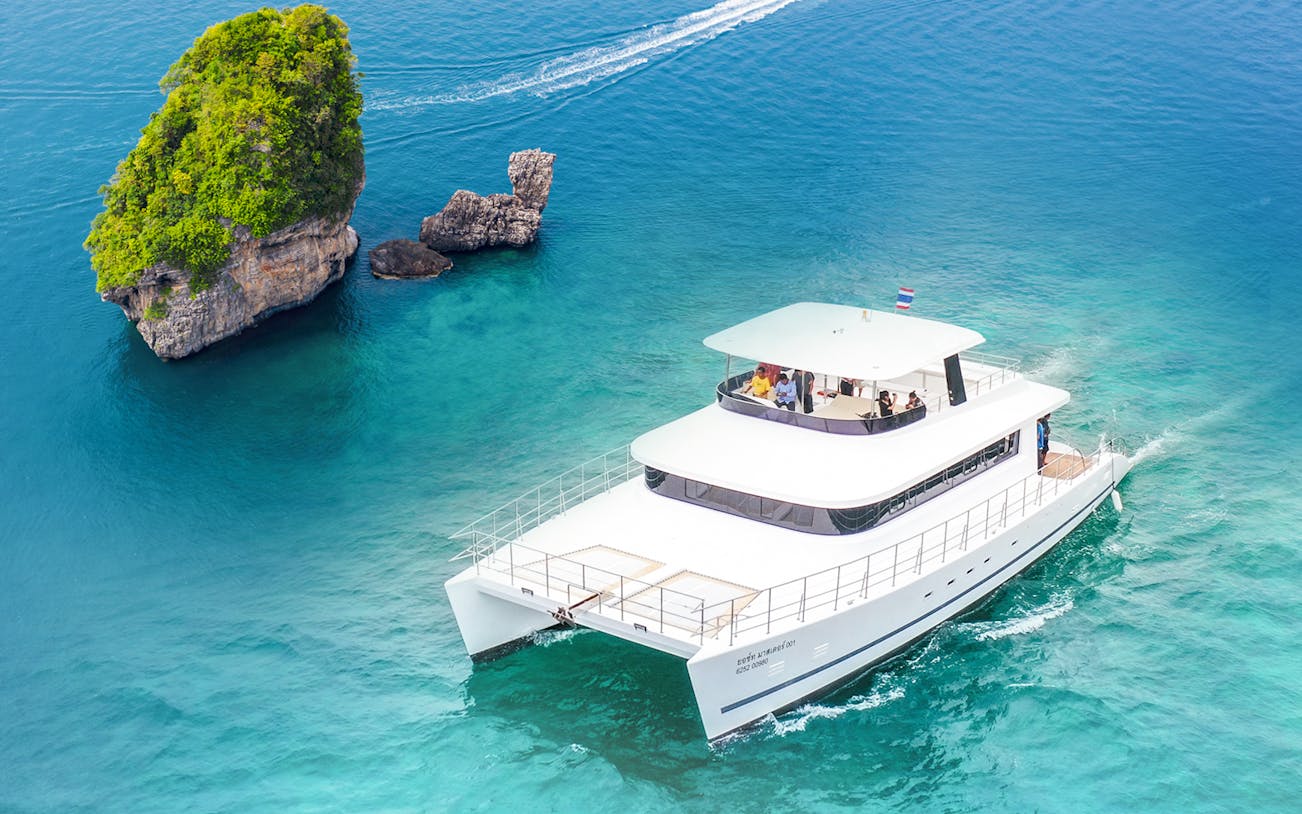Premium yacht sailing near limestone cliffs during James Bond Sunset Tour, Phuket, Thailand.