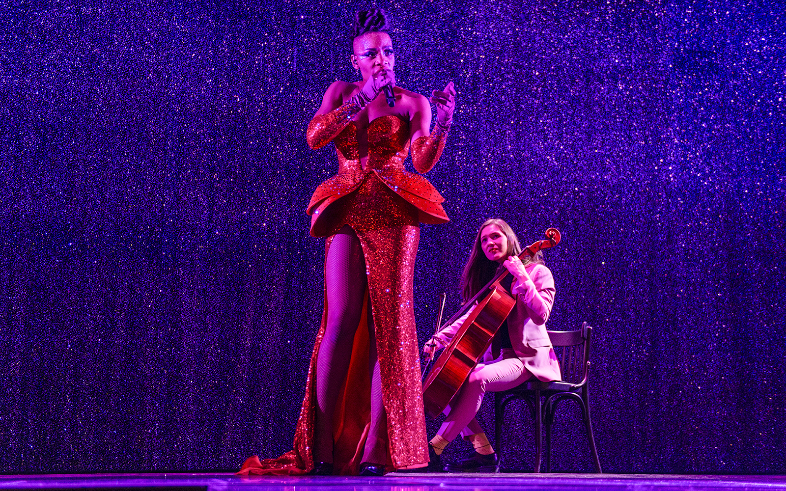 Performer singing with cellist at Paradis Latin festive show.