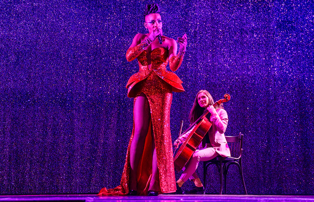 Performer singing with cellist at Paradis Latin festive show.