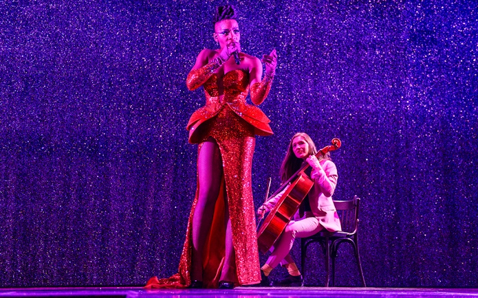 Performer singing with cellist at Paradis Latin festive show.