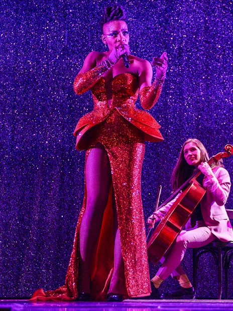 Performer singing with cellist at Paradis Latin festive show.