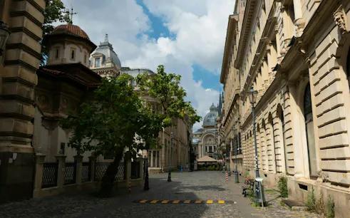 Historic street in Bucharest with ornate buildings and cobblestone path on the Beer Trail exploration game.