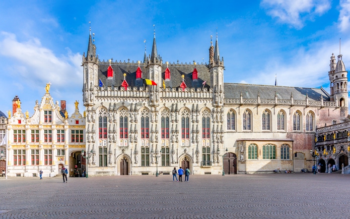 Bruges City Hall exterior with Gothic architecture and flags, Belgium.