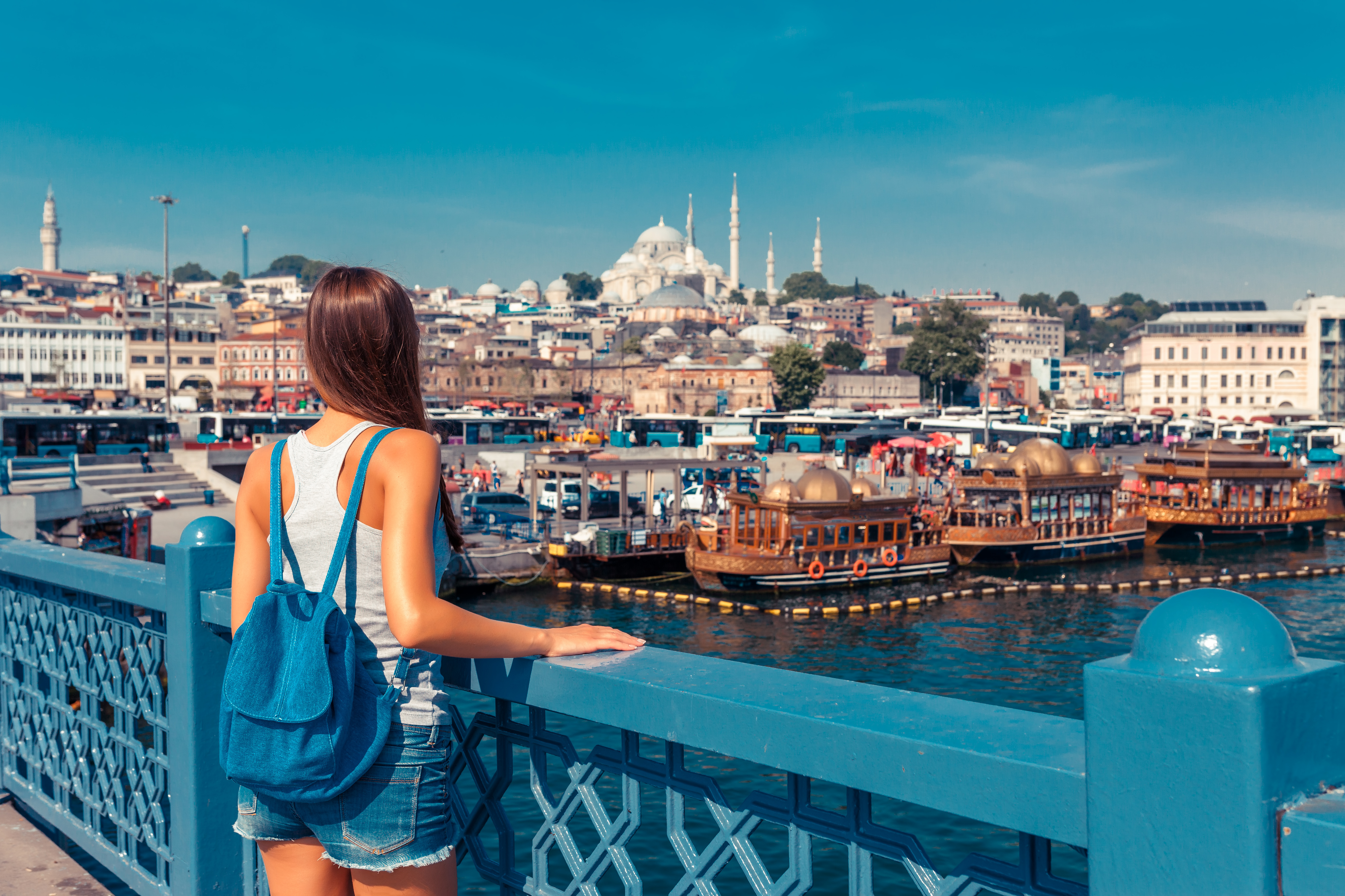 Woman overlooking boats and cityscape from Galata Bridge, Istanbul.