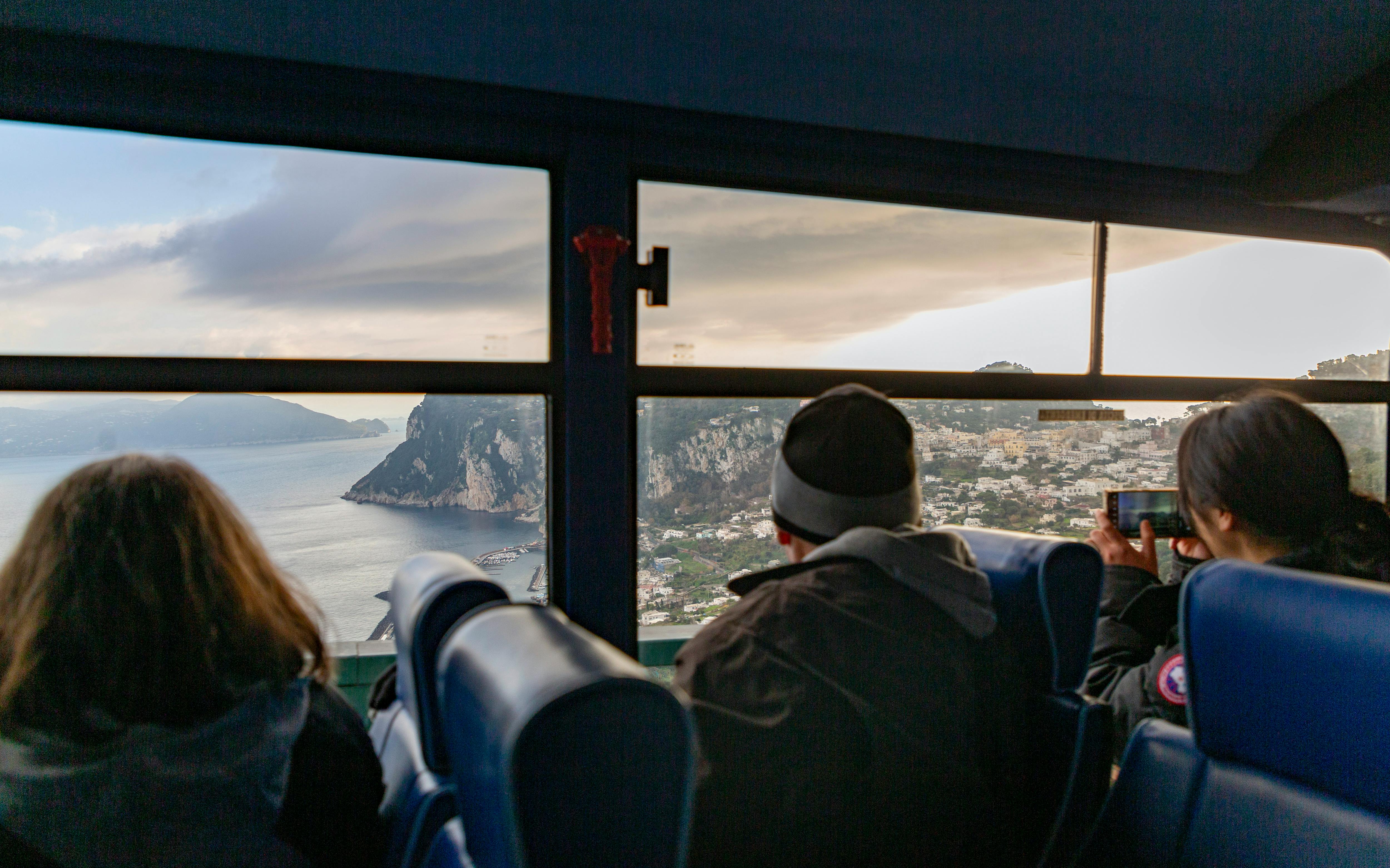 Bus passengers view Capri coastline through window.