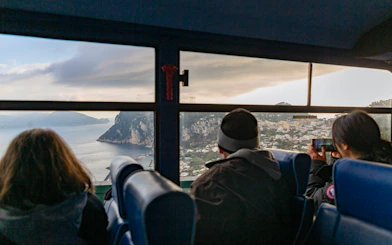 Bus passengers view Capri coastline through window.