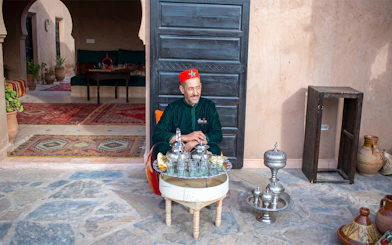 Berber man serving traditional breakfast in Marrakesh courtyard.