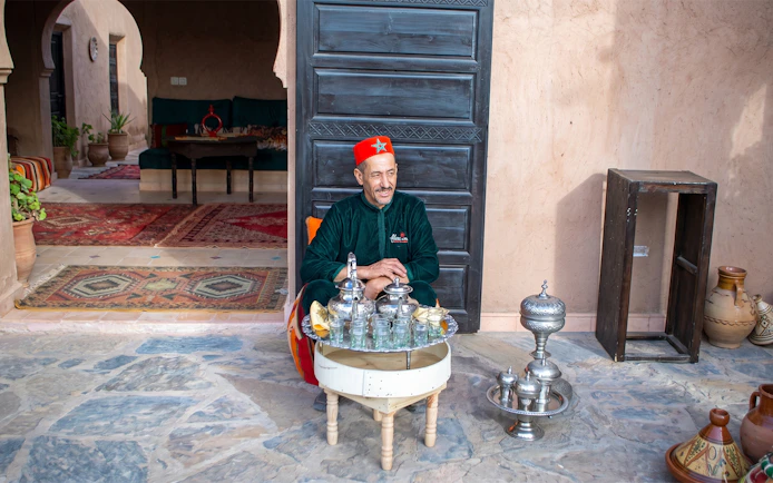 Berber man serving traditional breakfast in Marrakesh courtyard.