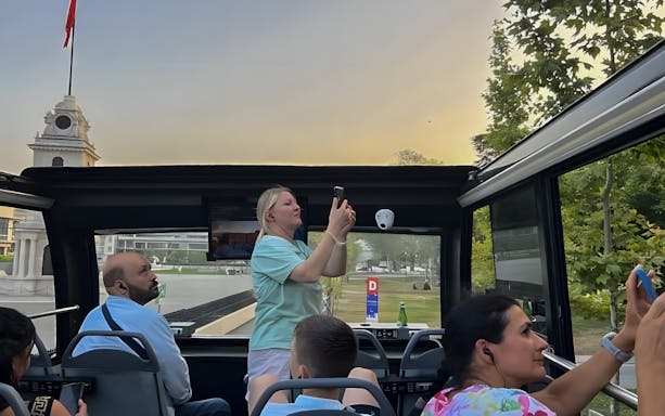 Passengers on a double-decker bus tour in Istanbul capturing views of the cityscape.