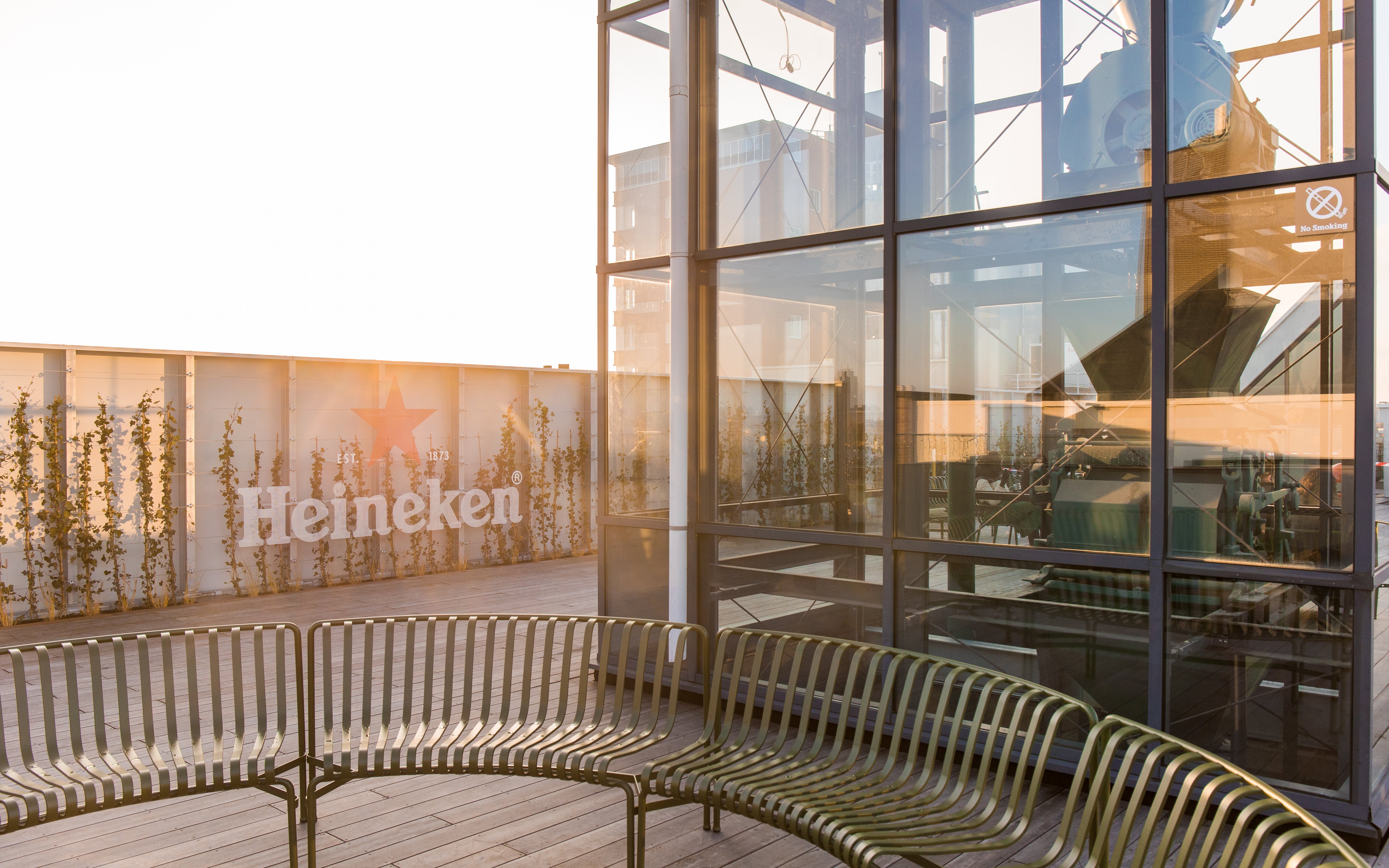 Heineken rooftop with glass structure and seating area at sunset.
