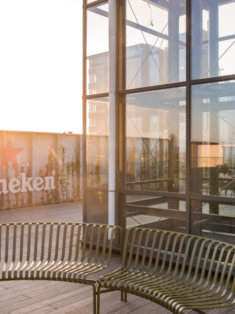 Heineken rooftop with glass structure and seating area at sunset.