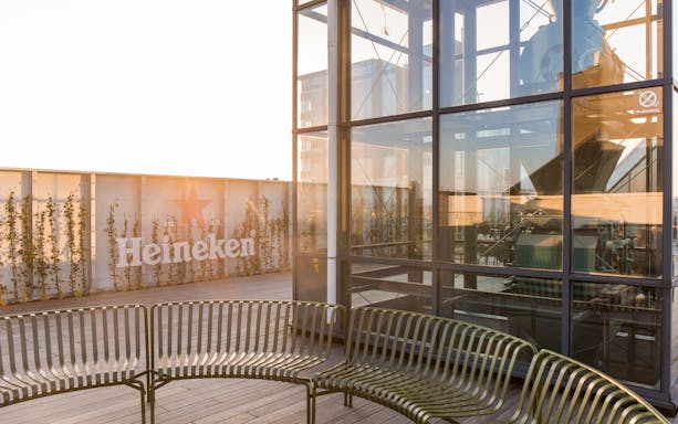 Heineken rooftop with glass structure and seating area at sunset.