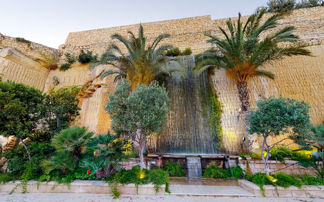 Limestone waterfall and palm trees at The Limestone Heritage, Malta.
