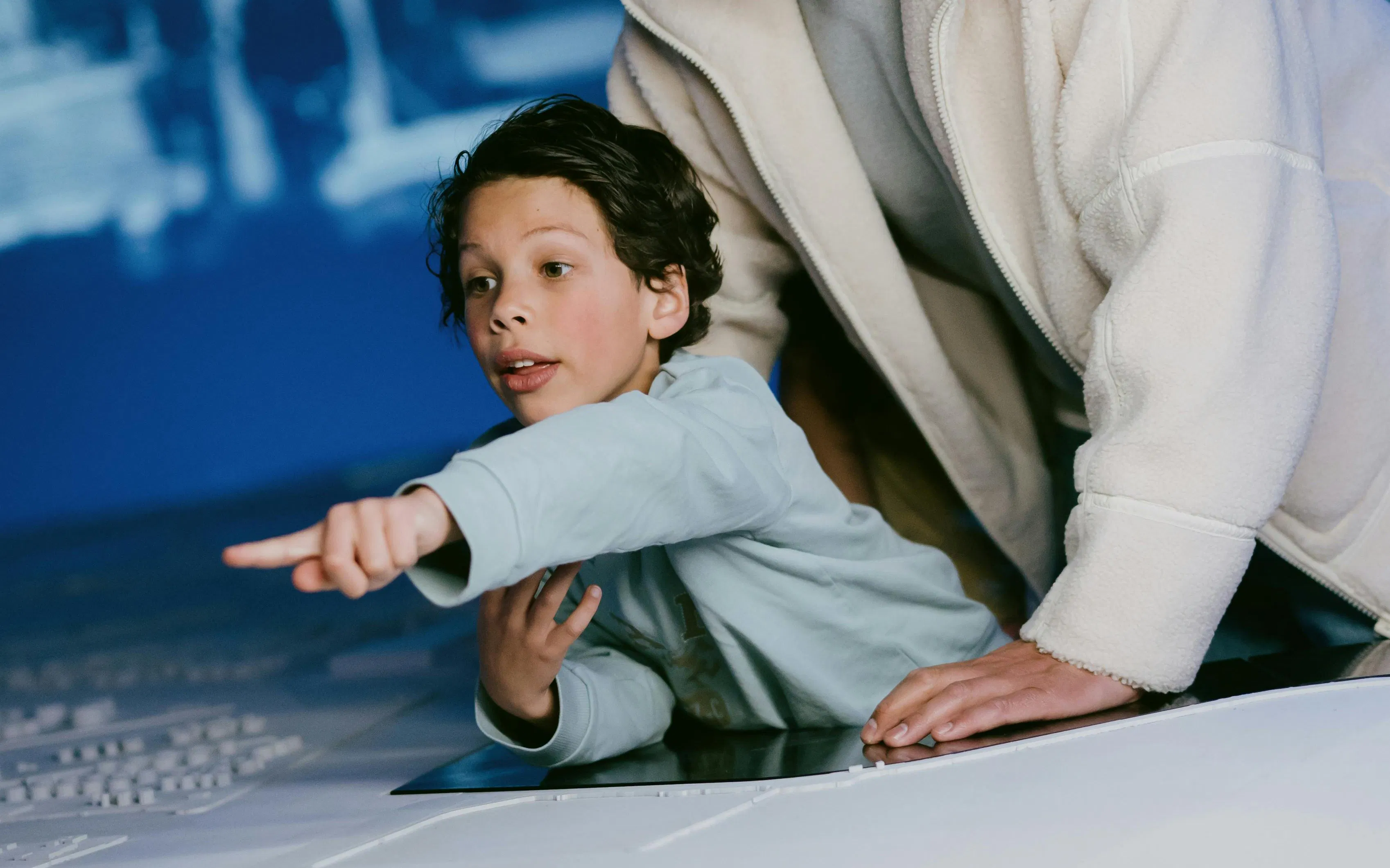 Child pointing at interactive exhibit in Amsterdam museum.