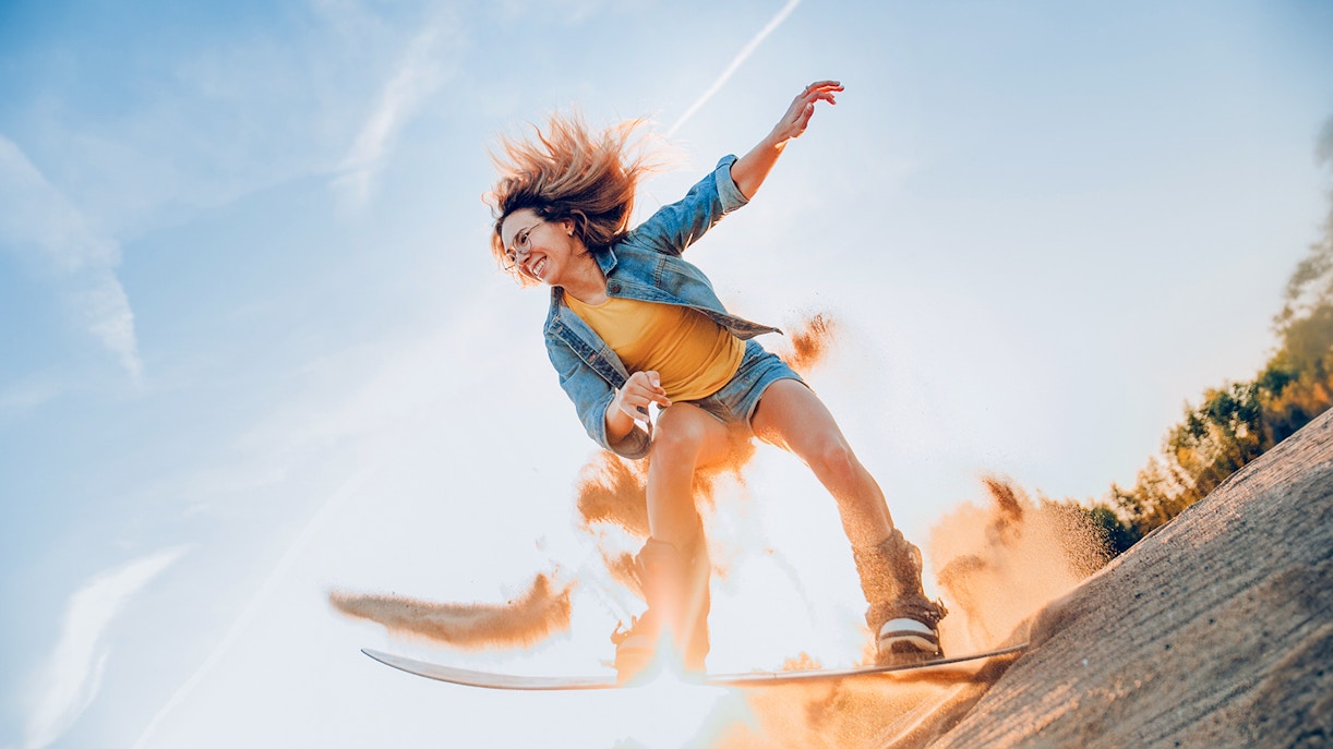 Une femme faisant du sandboard dans le désert