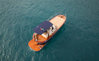 Cruise boat on Amalfi Coast waters with Italian flag.