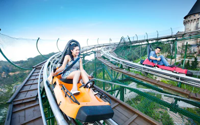 Couples riding Alpine Coaster at Sun World with scenic mountain views.