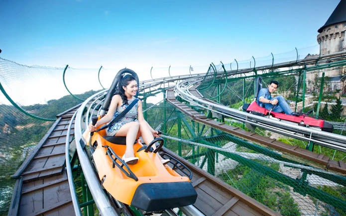 Couples riding Alpine Coaster at Sun World with scenic mountain views.