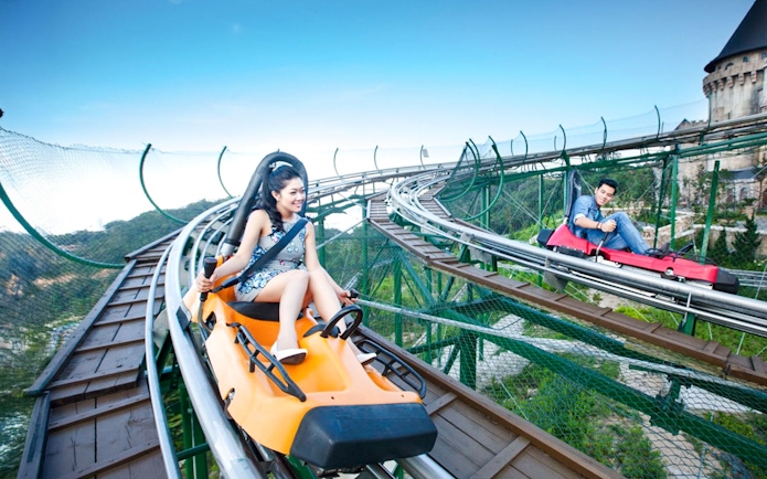 Couples riding Alpine Coaster at Sun World with scenic mountain views.