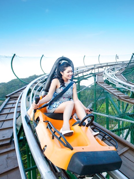 Couples riding Alpine Coaster at Sun World with scenic mountain views.