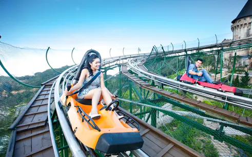 Couples riding Alpine Coaster at Sun World with scenic mountain views.